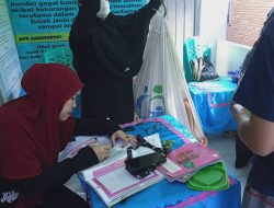 Kader kesehatan sedang menimbang balita di posyandu